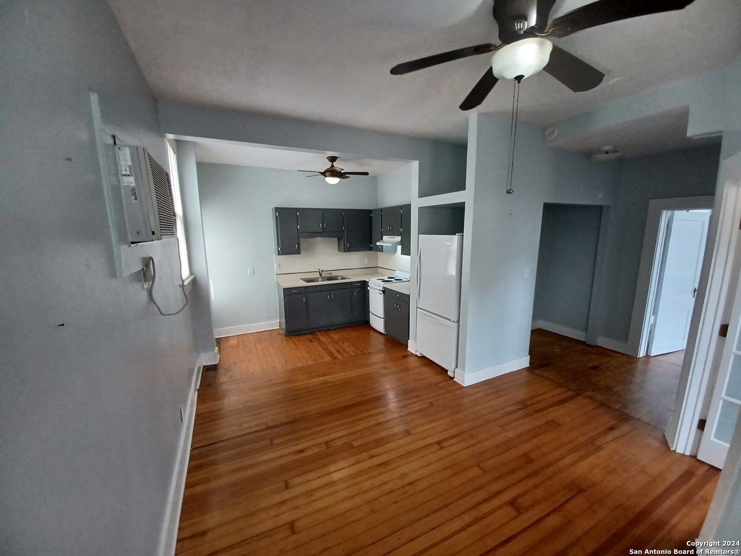 a room with a wooden floor and chandelier fan