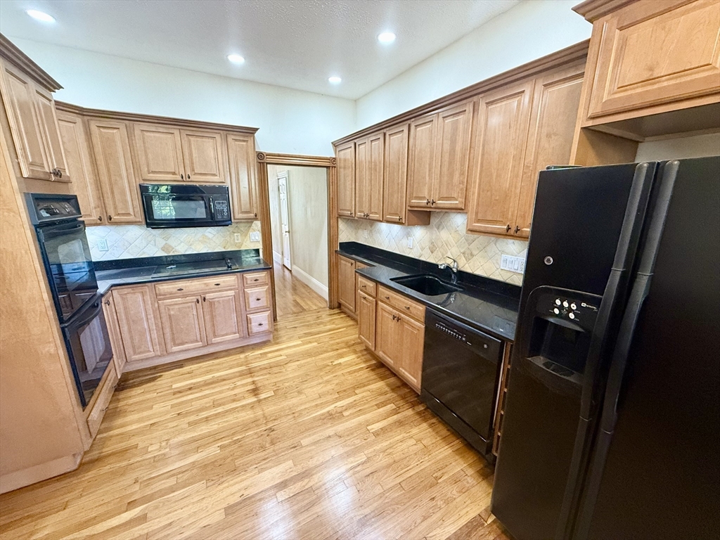 a kitchen with granite countertop a refrigerator stove top oven and sink