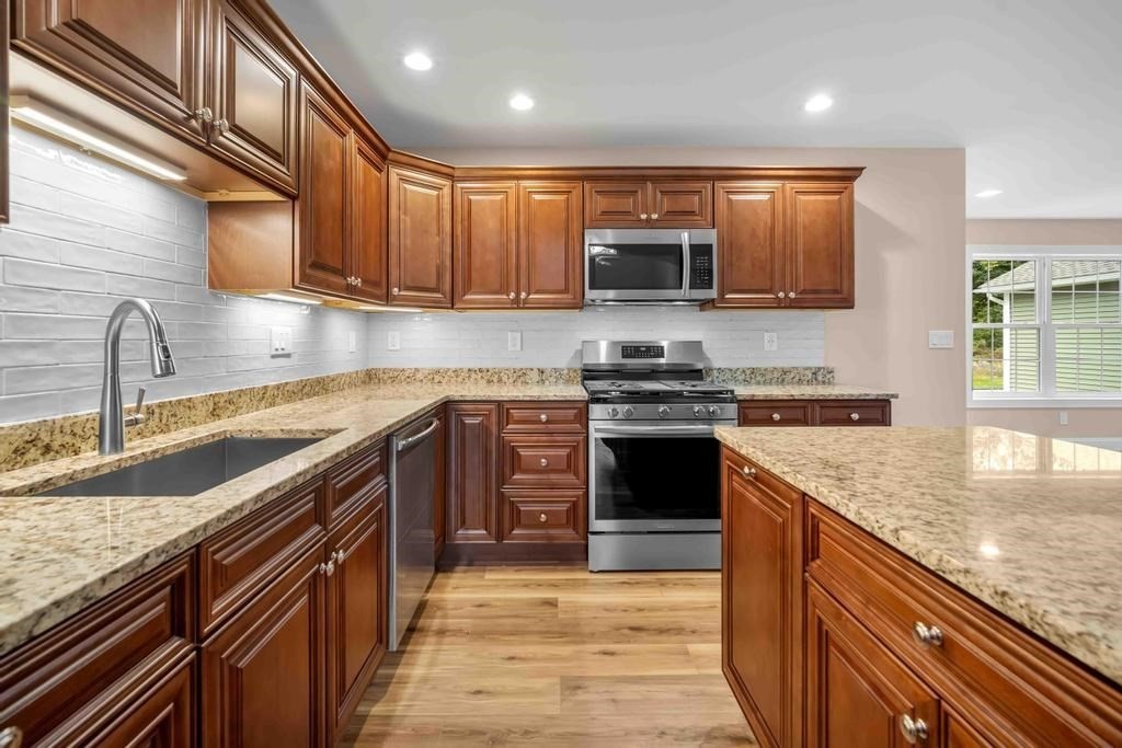 a kitchen with stainless steel appliances granite countertop a sink stove and refrigerator