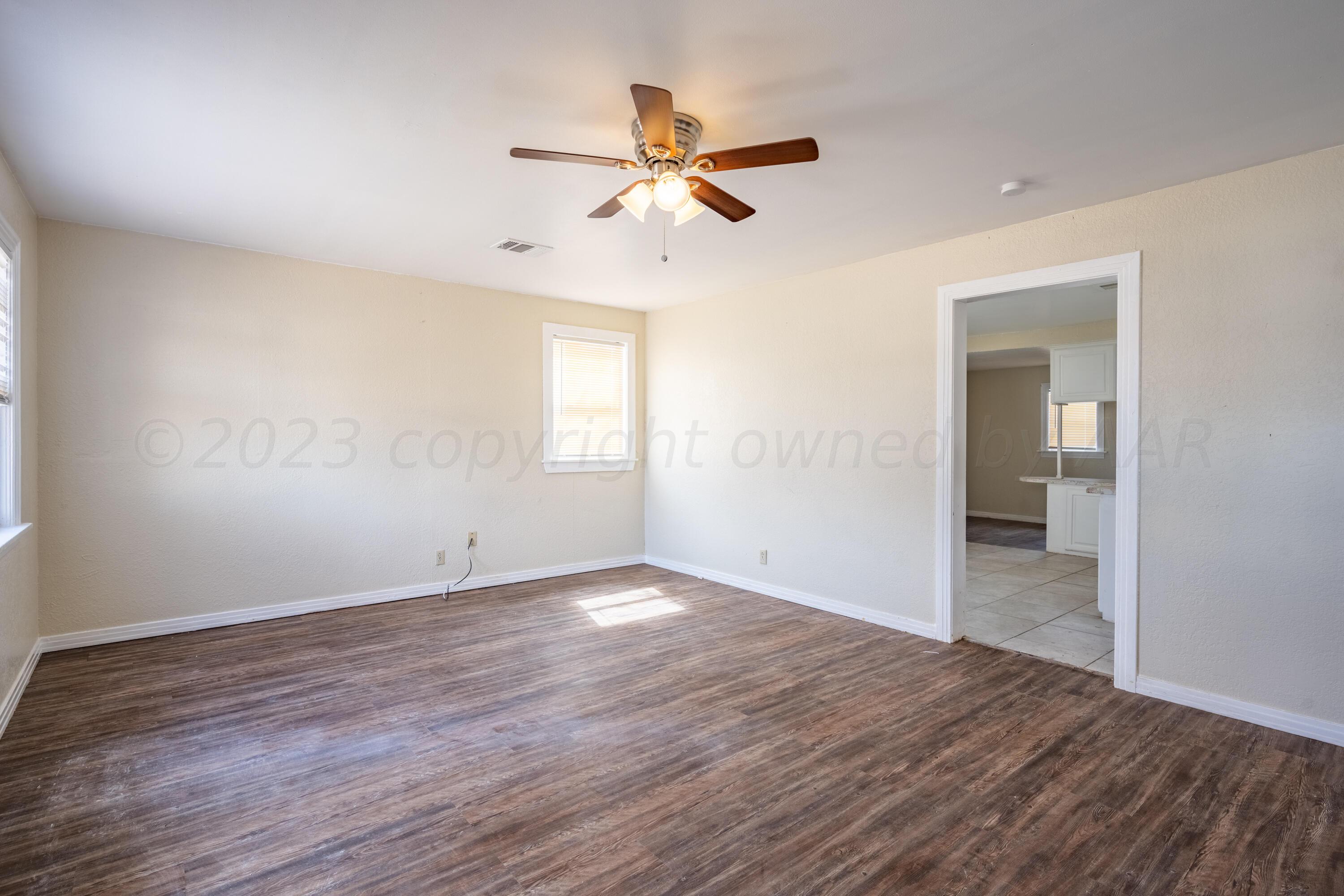 a view of empty room with wooden floor and fan