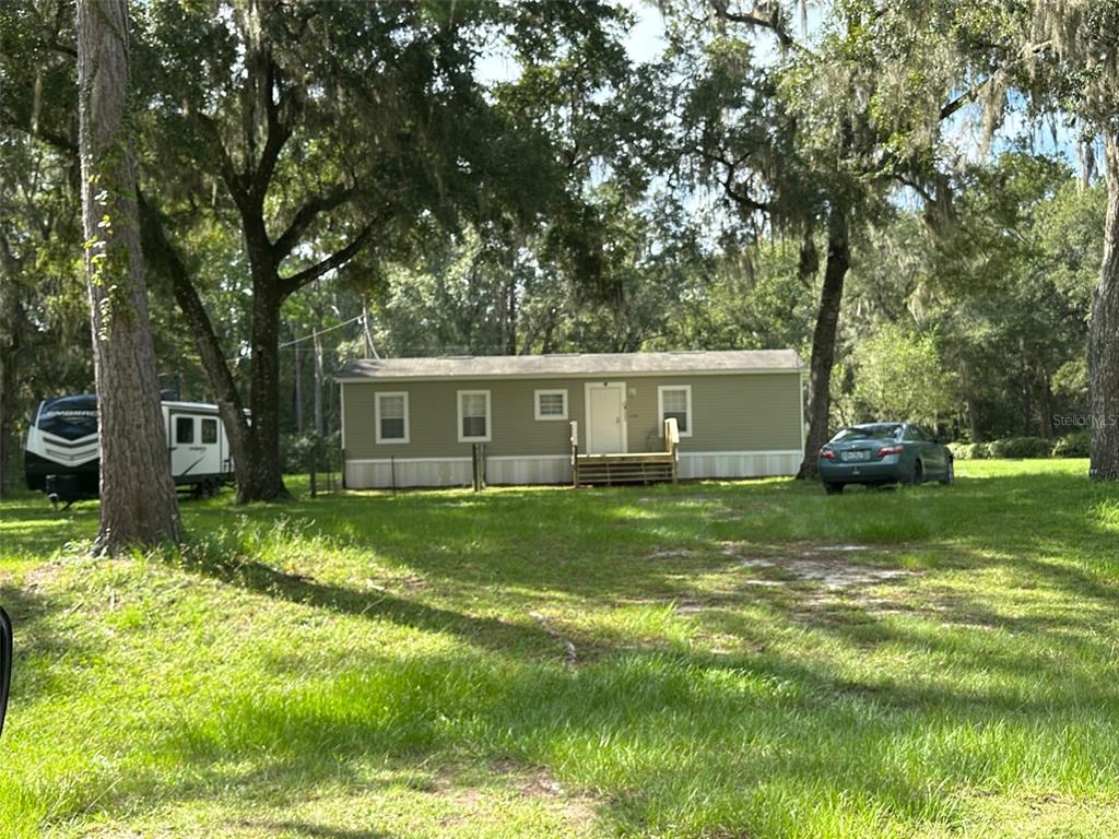 a view of a house with a big yard and large trees