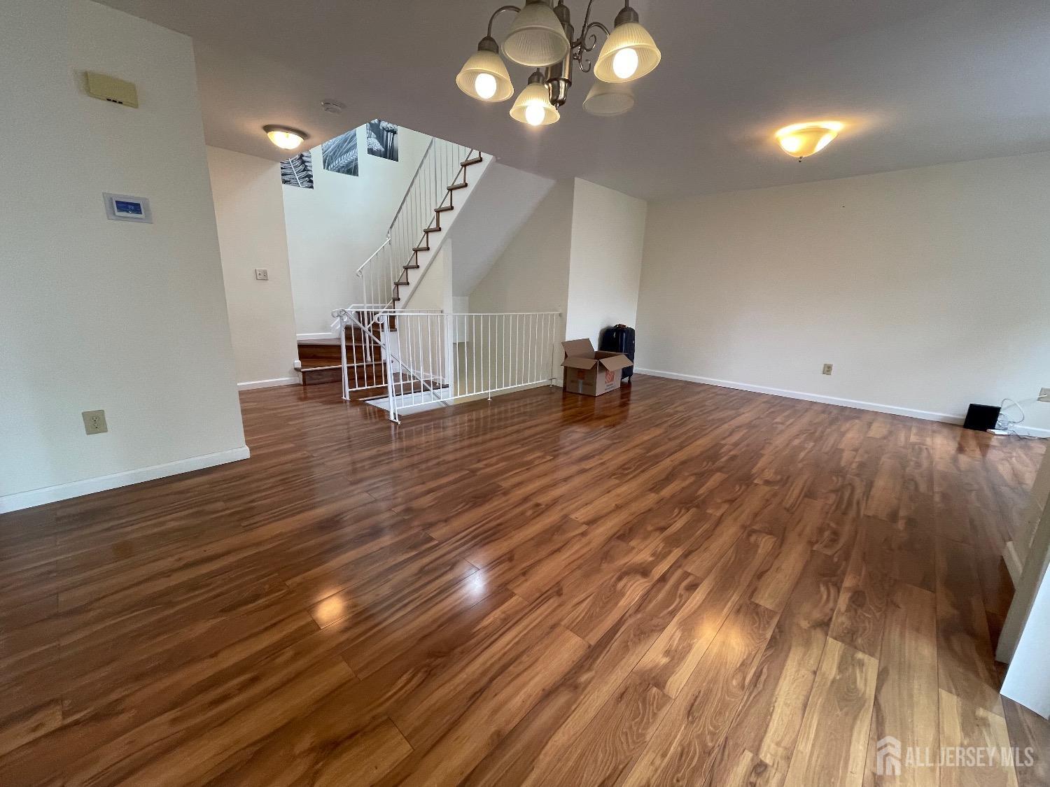 a view of an empty room with wooden floor and a ceiling fan