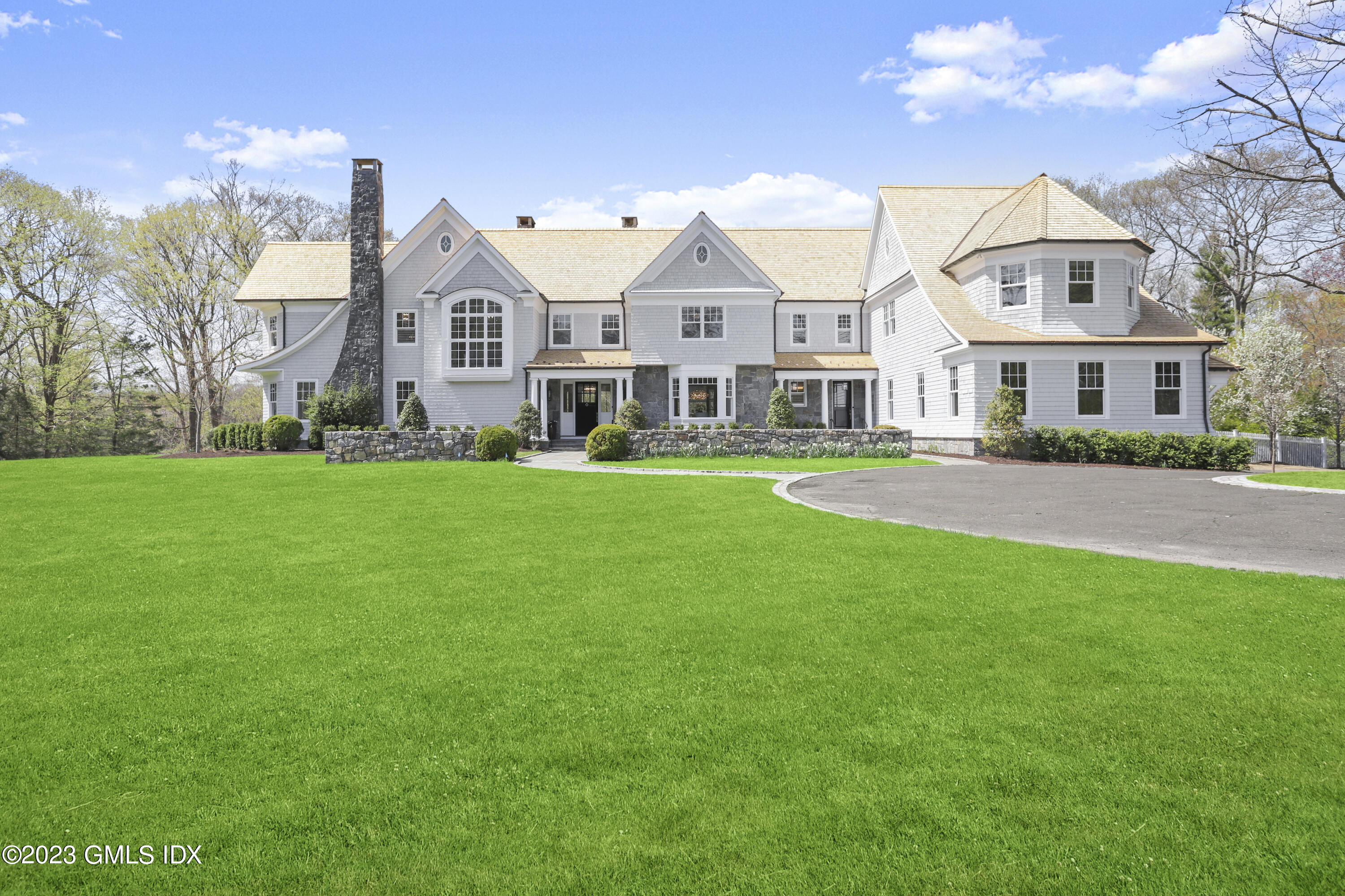 a view of a white house next to a yard with big trees