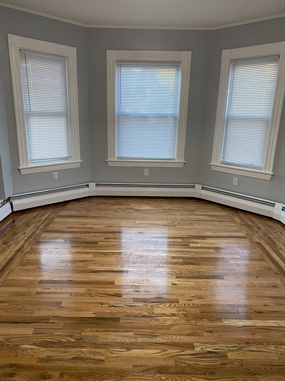 a view of an empty room with wooden floor and window