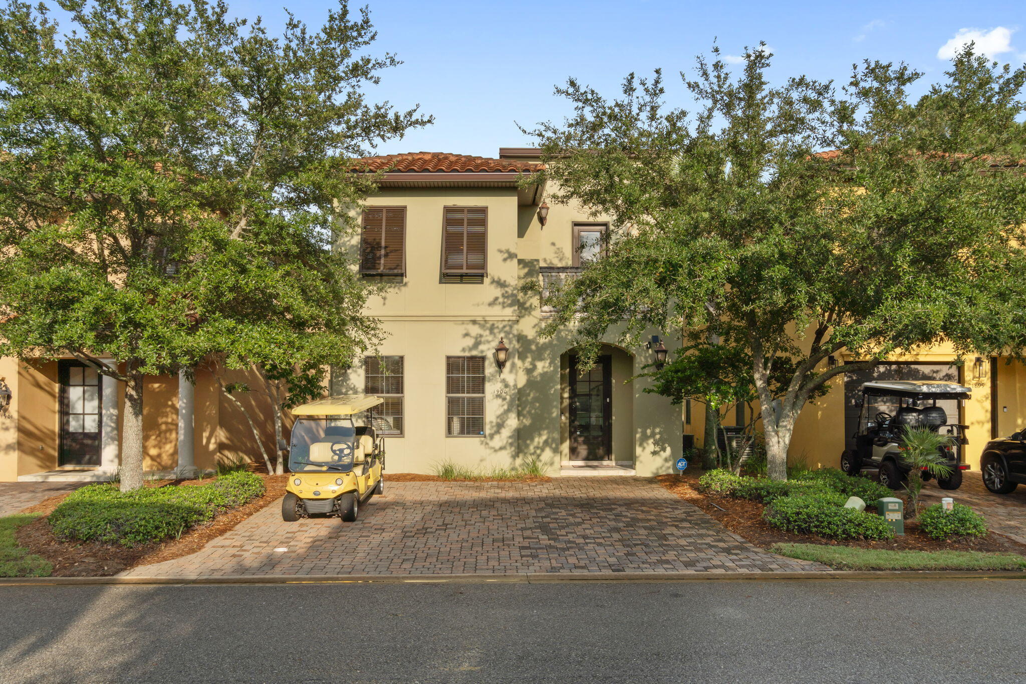 a view of a house with brick walls and a tree with flower plants in front of main door