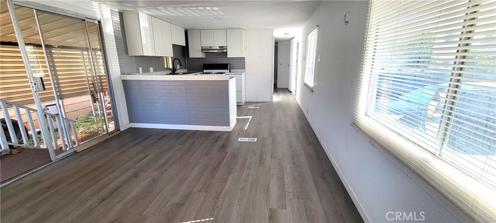 a kitchen with stainless steel appliances wooden floors and large window