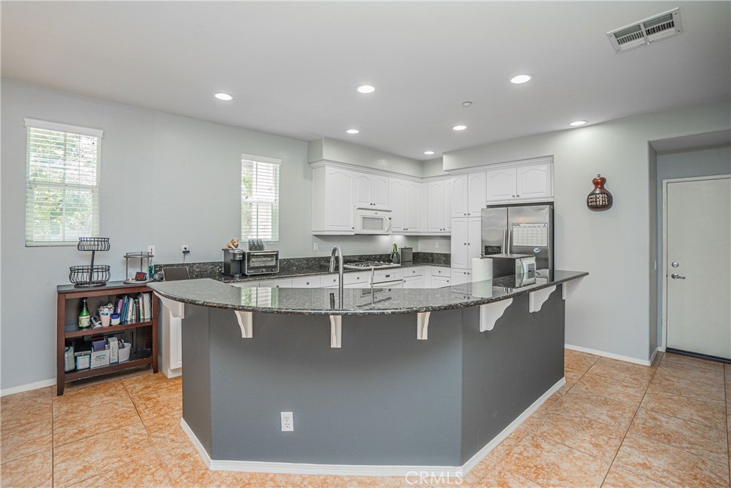 a large kitchen with kitchen island a sink a stove a refrigerator and a dining table view