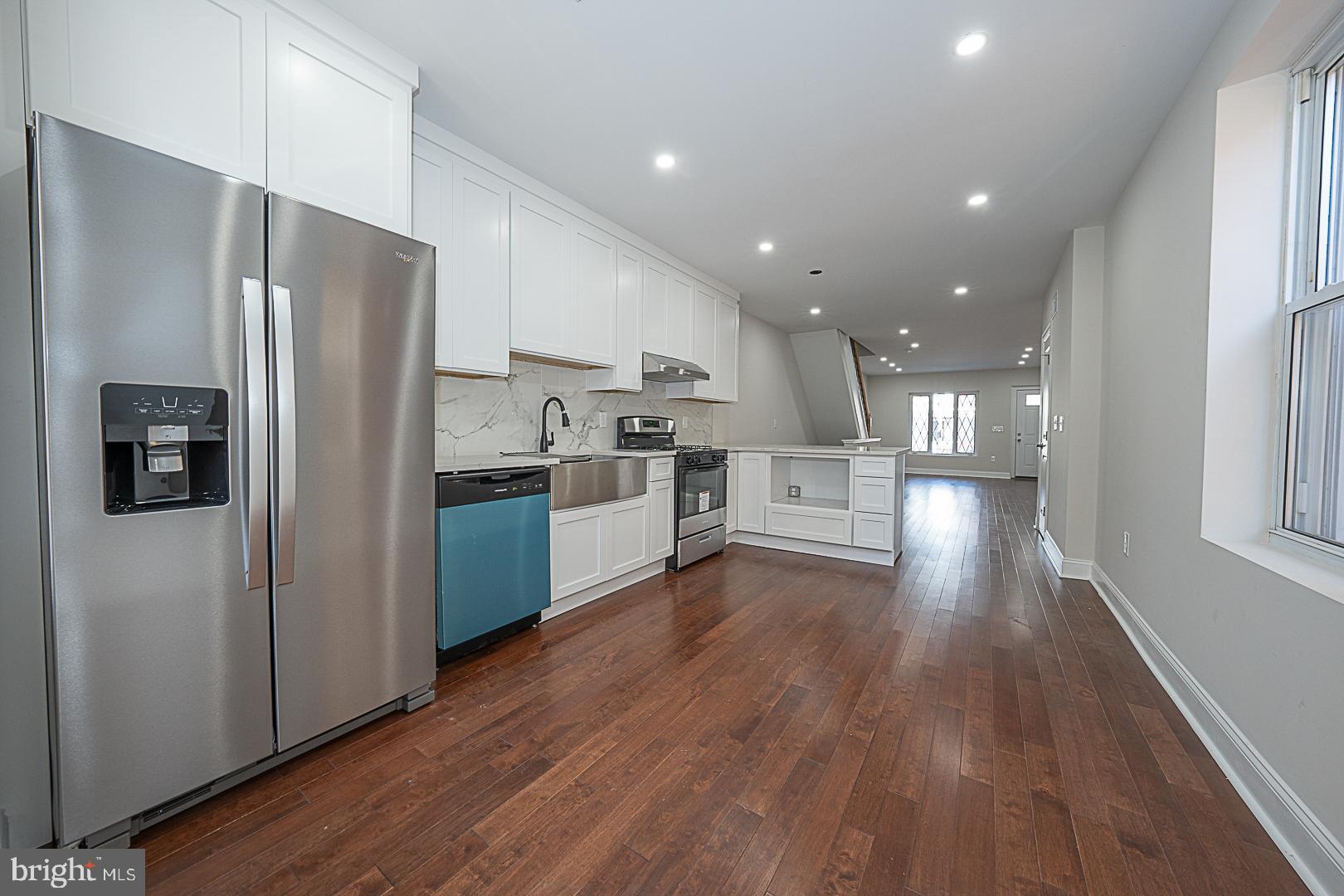 a kitchen with stainless steel appliances a refrigerator sink and wooden floor