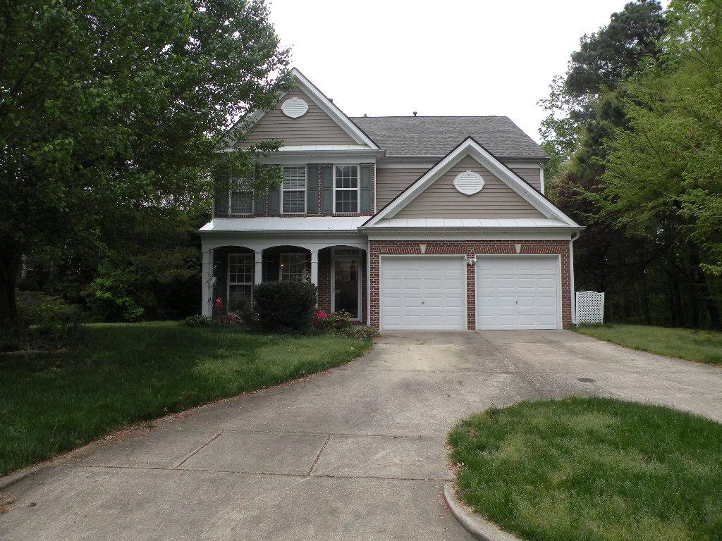 a front view of a house with a garden and trees