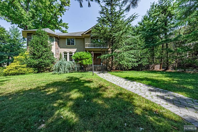 a view of house in front of a big yard with large trees