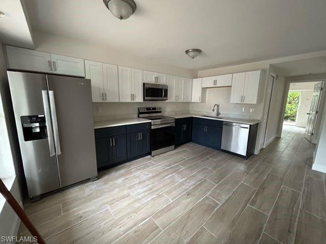 Kitchen featuring light hardwood / wood-style floors, appliances with stainless steel finishes, sink, and white cabinets