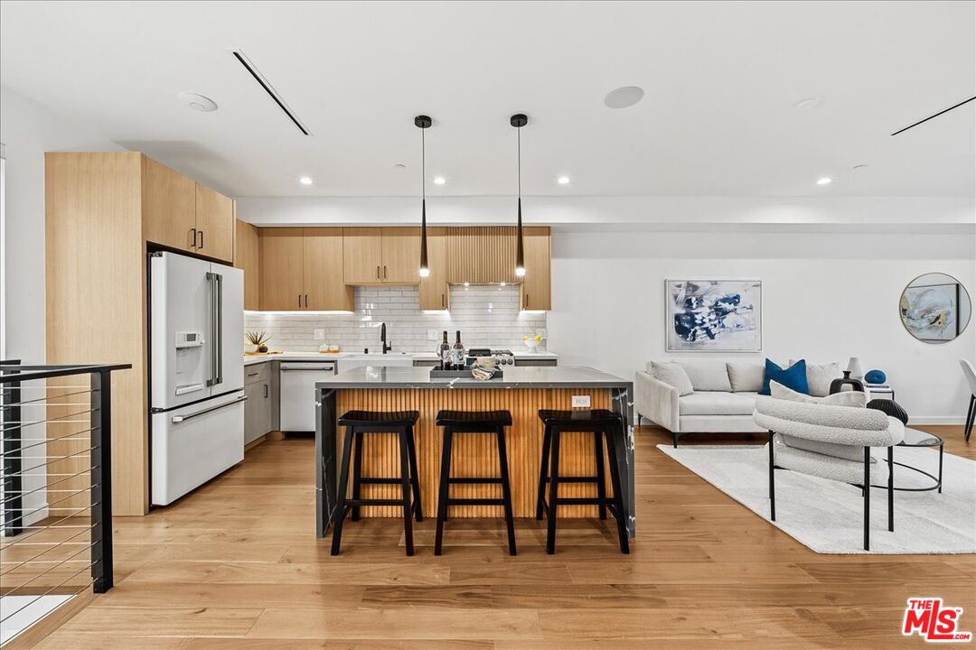 a living room with kitchen island a table and chairs with wooden floor