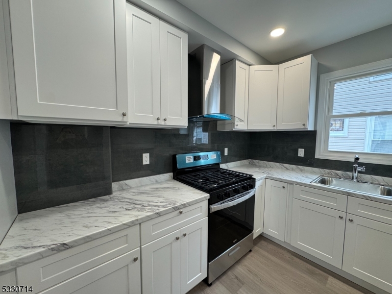 a kitchen with granite countertop white cabinets and black appliances