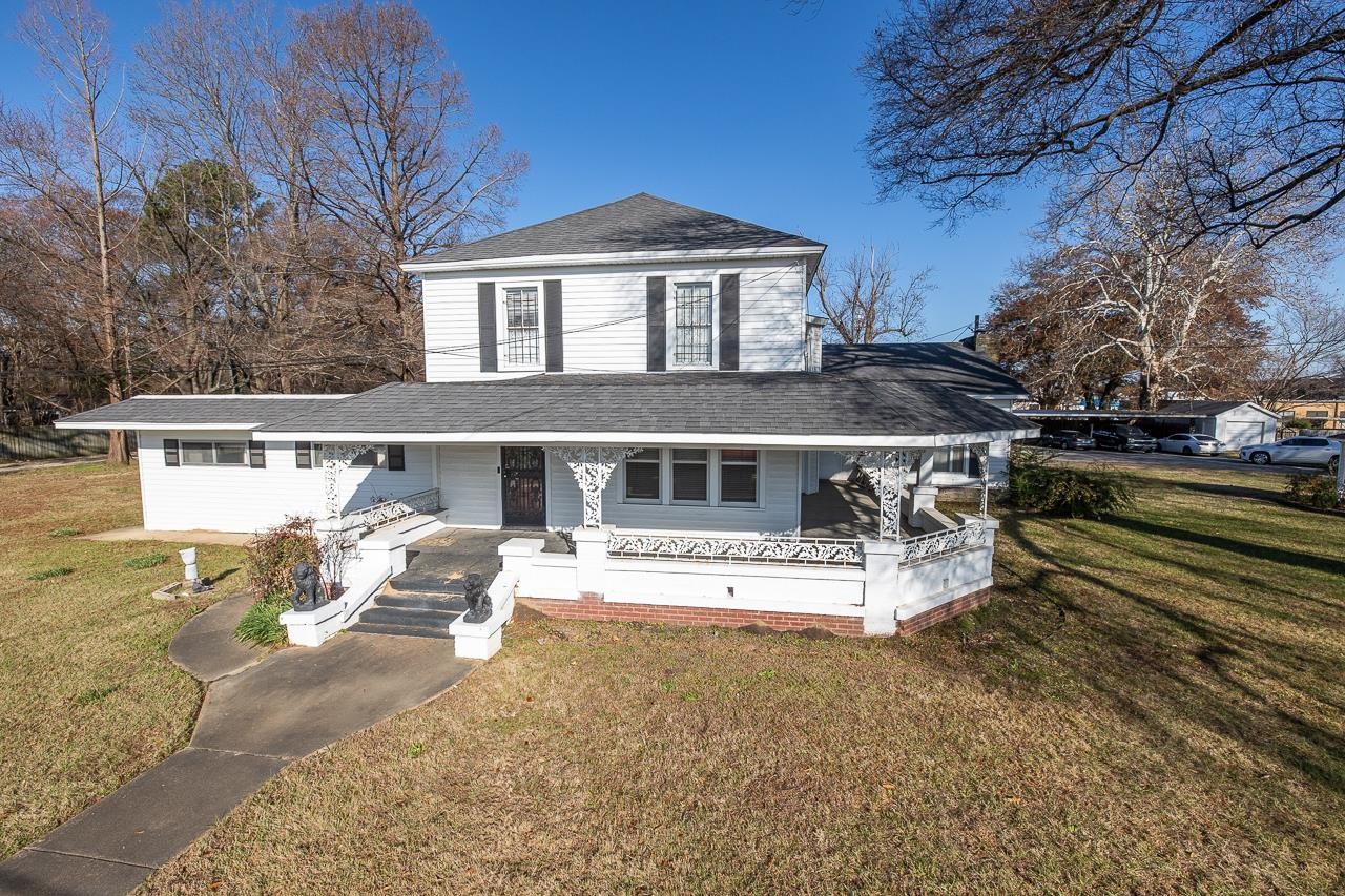 View of front of home with covered porch and a front lawn