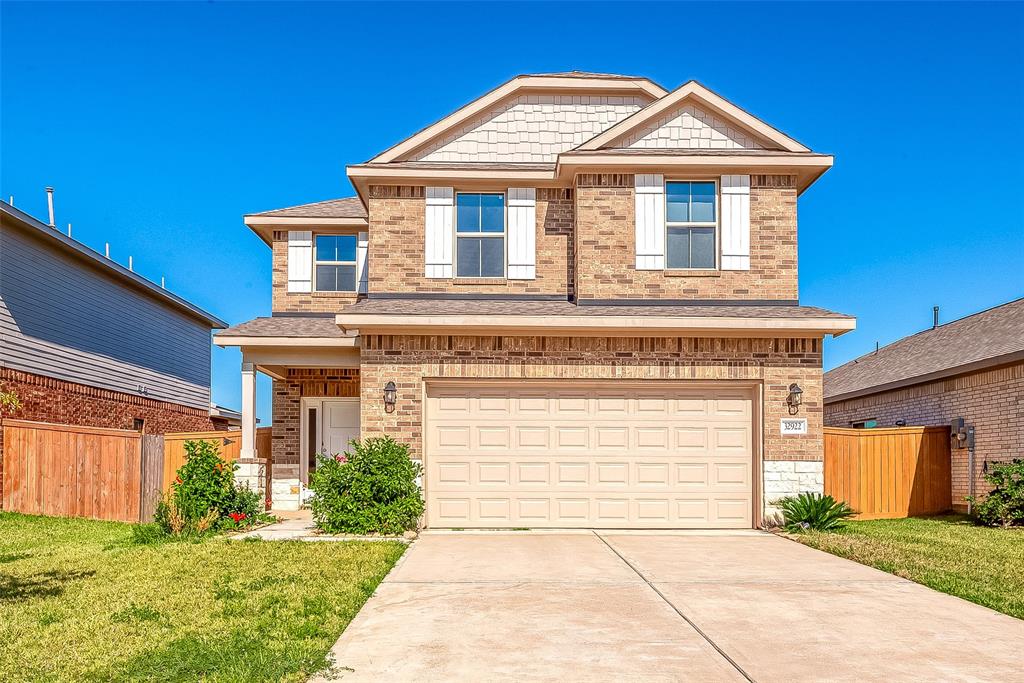 This is a modern two-story brick home featuring a two-car garage, a welcoming entrance, and a neatly maintained lawn.