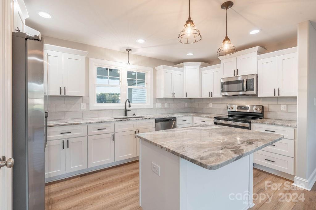 a kitchen with granite countertop a sink a counter space appliances and cabinets