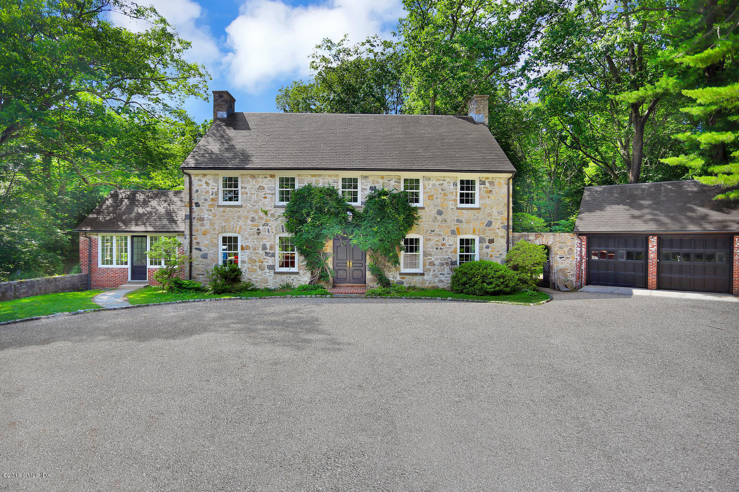 front view of house with a yard and large trees