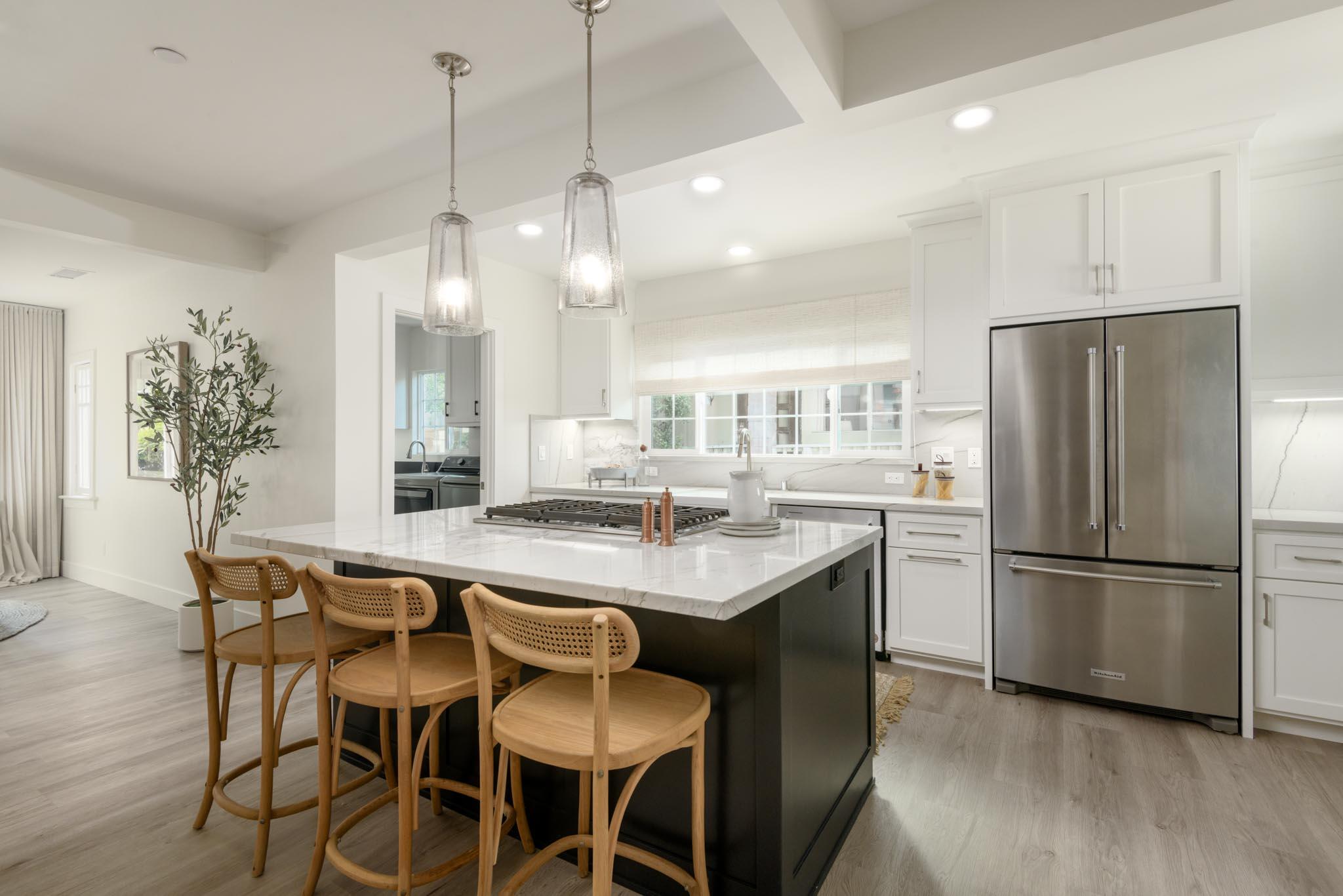 a kitchen with stainless steel appliances a dining table chairs refrigerator and sink