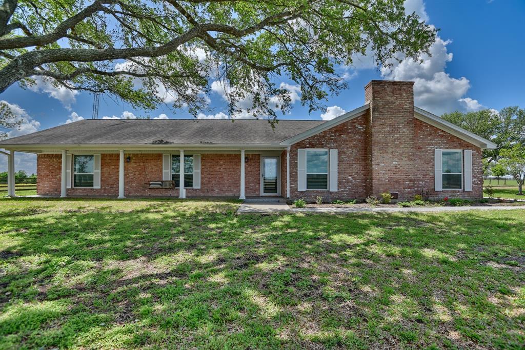 a brick house next to a yard with a large tree