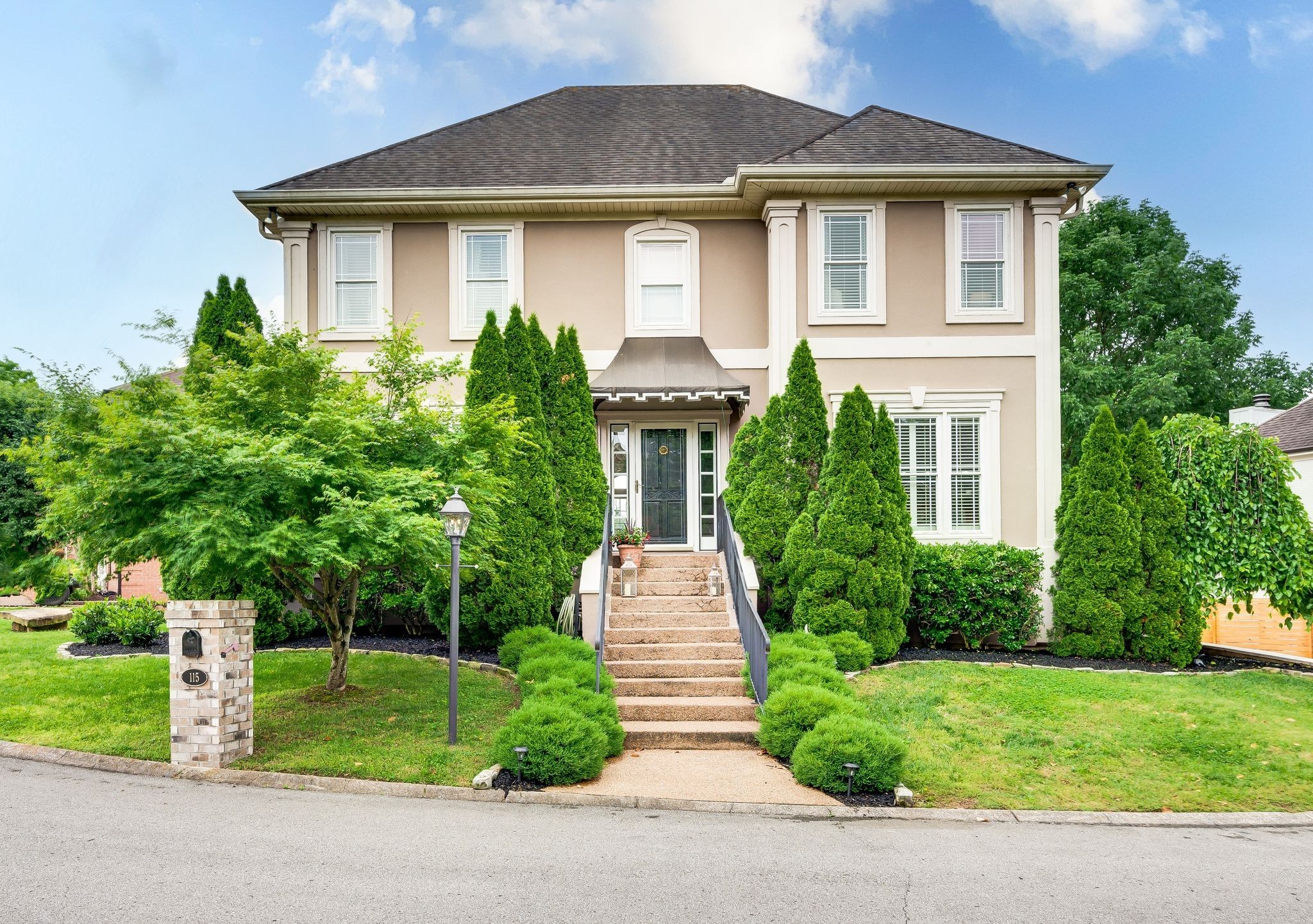 a front view of a house with a yard and trees