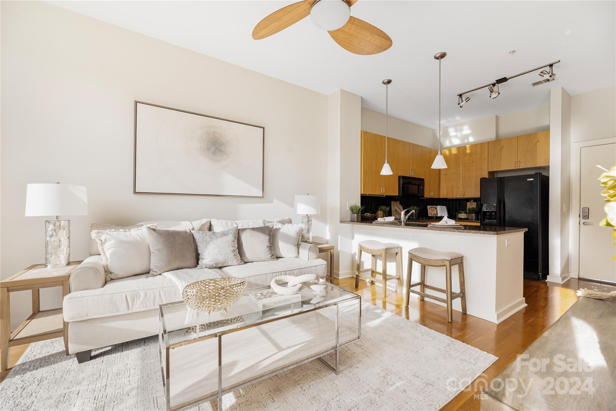 a living room with furniture a refrigerator and kitchen view