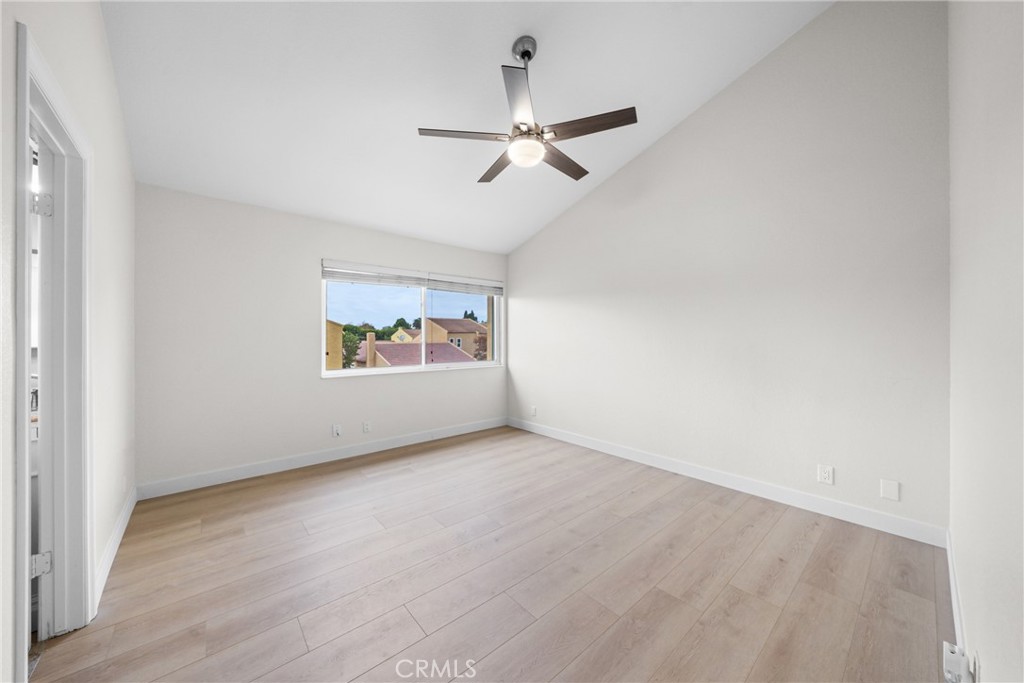 an empty room with wooden floor ceiling fan and windows