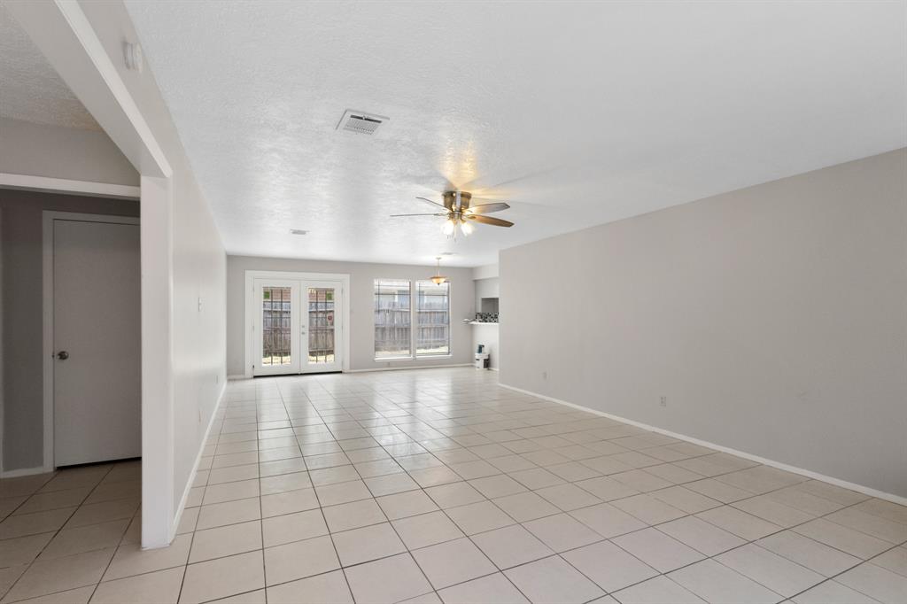 an empty room with chandelier fan and windows