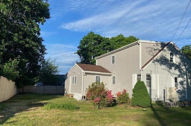 a view of a white house with a small yard plants and a large tree