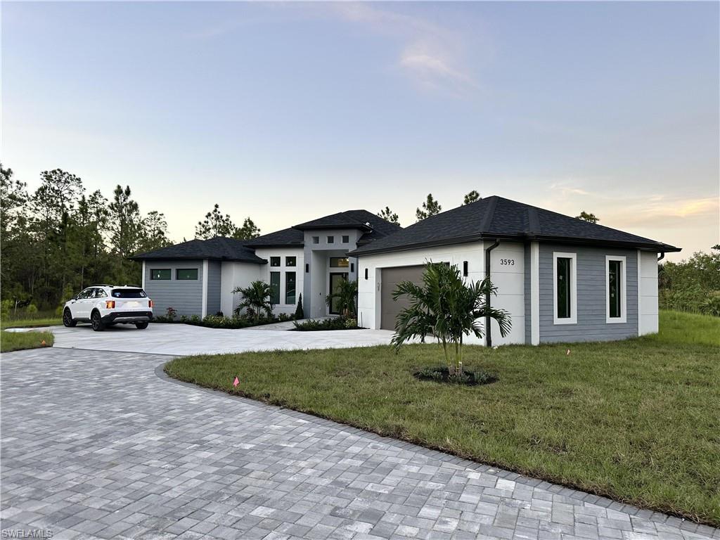 View of front of property with a garage and a yard