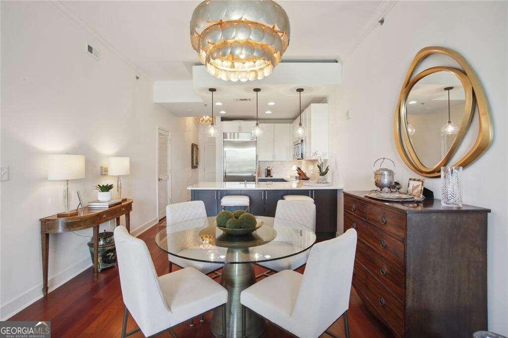 a dining room with wooden floor a chandelier a wooden table and chairs