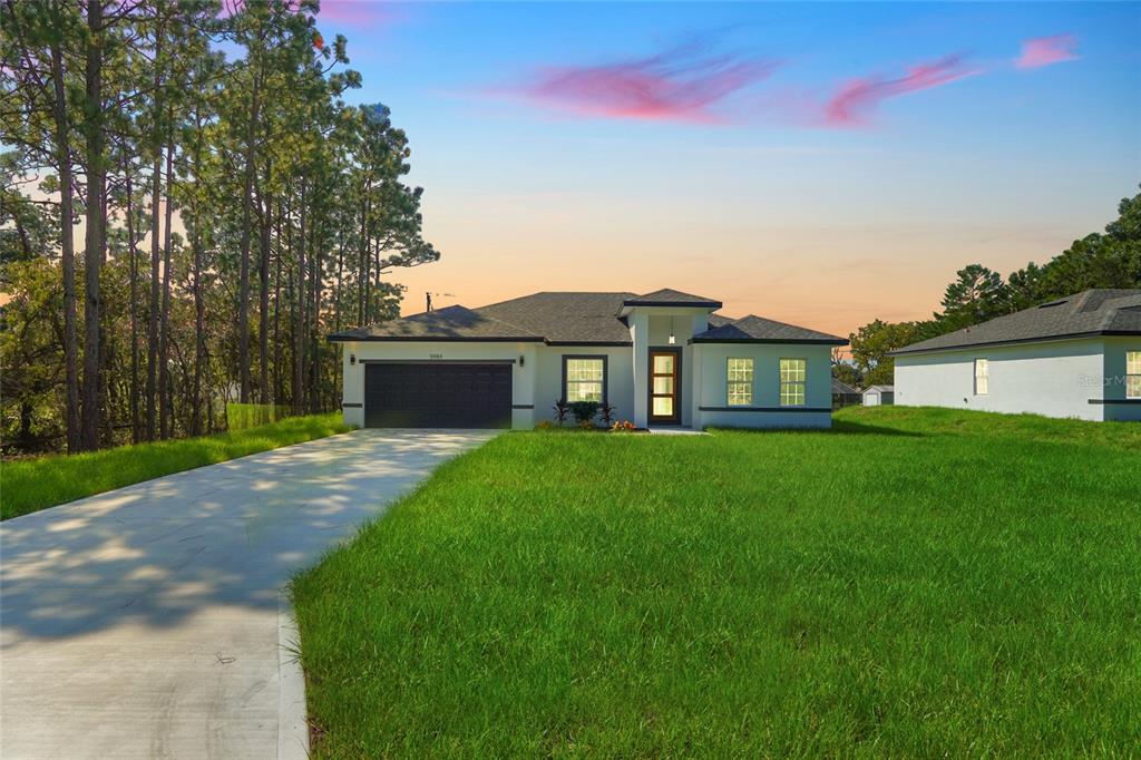 a front view of a house with a yard and trees