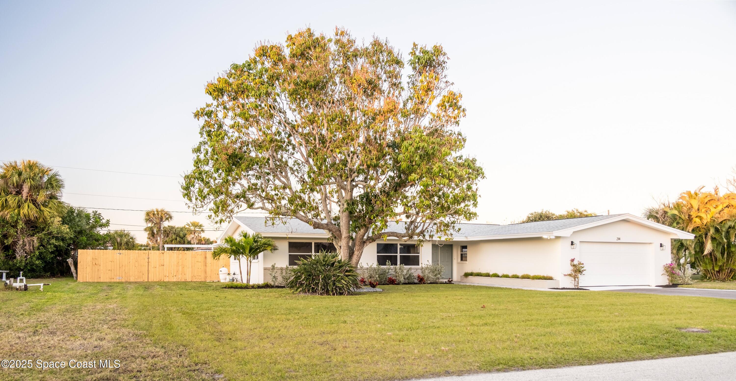 a front view of a house with a garden and trees