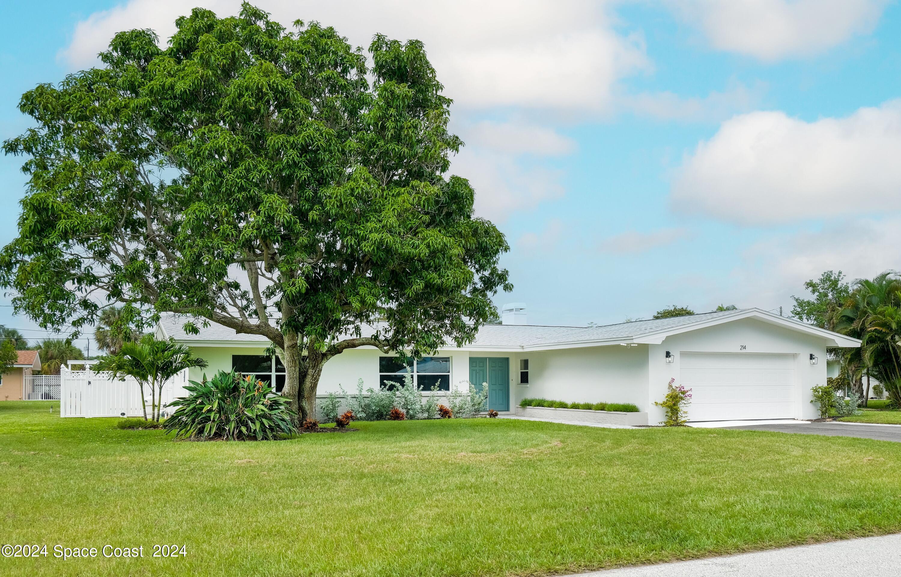 a front view of a house with a yard and trees