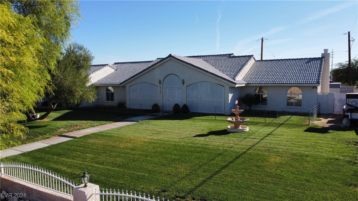 Front gated grass yard with mature trees and water