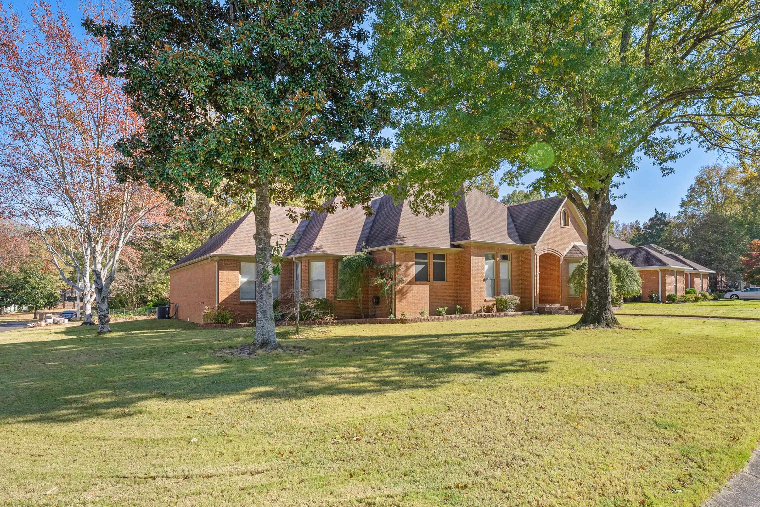 a view of a big house with a big yard and large trees