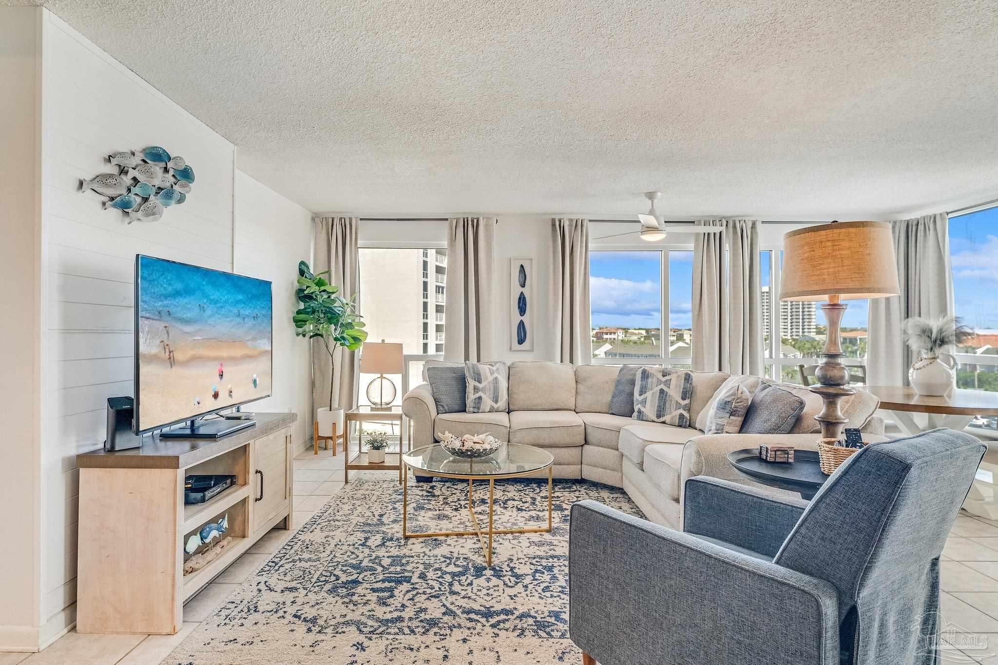 a living room with furniture floor to ceiling window and a rug