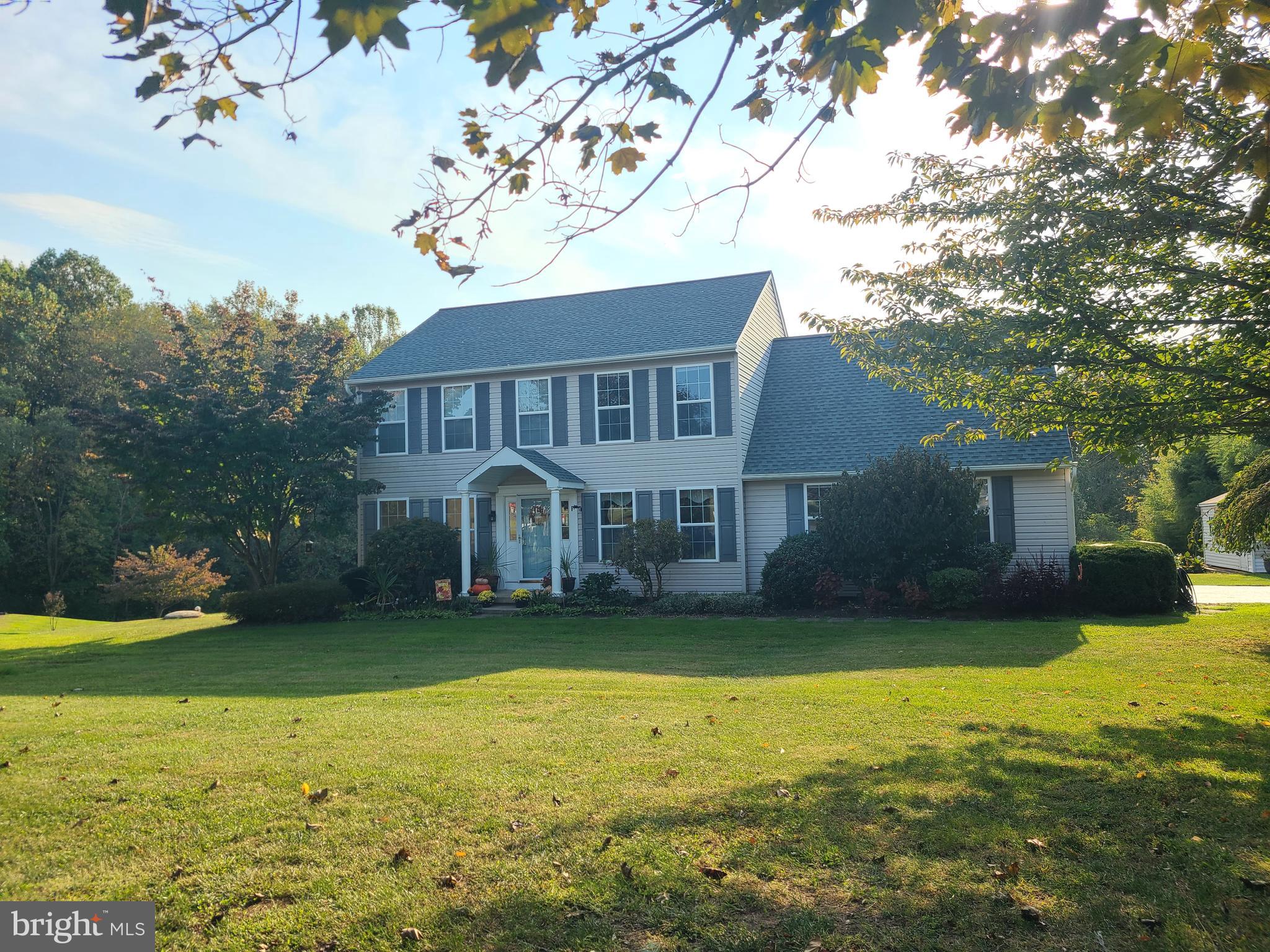 a view of a house next to a big yard with large trees