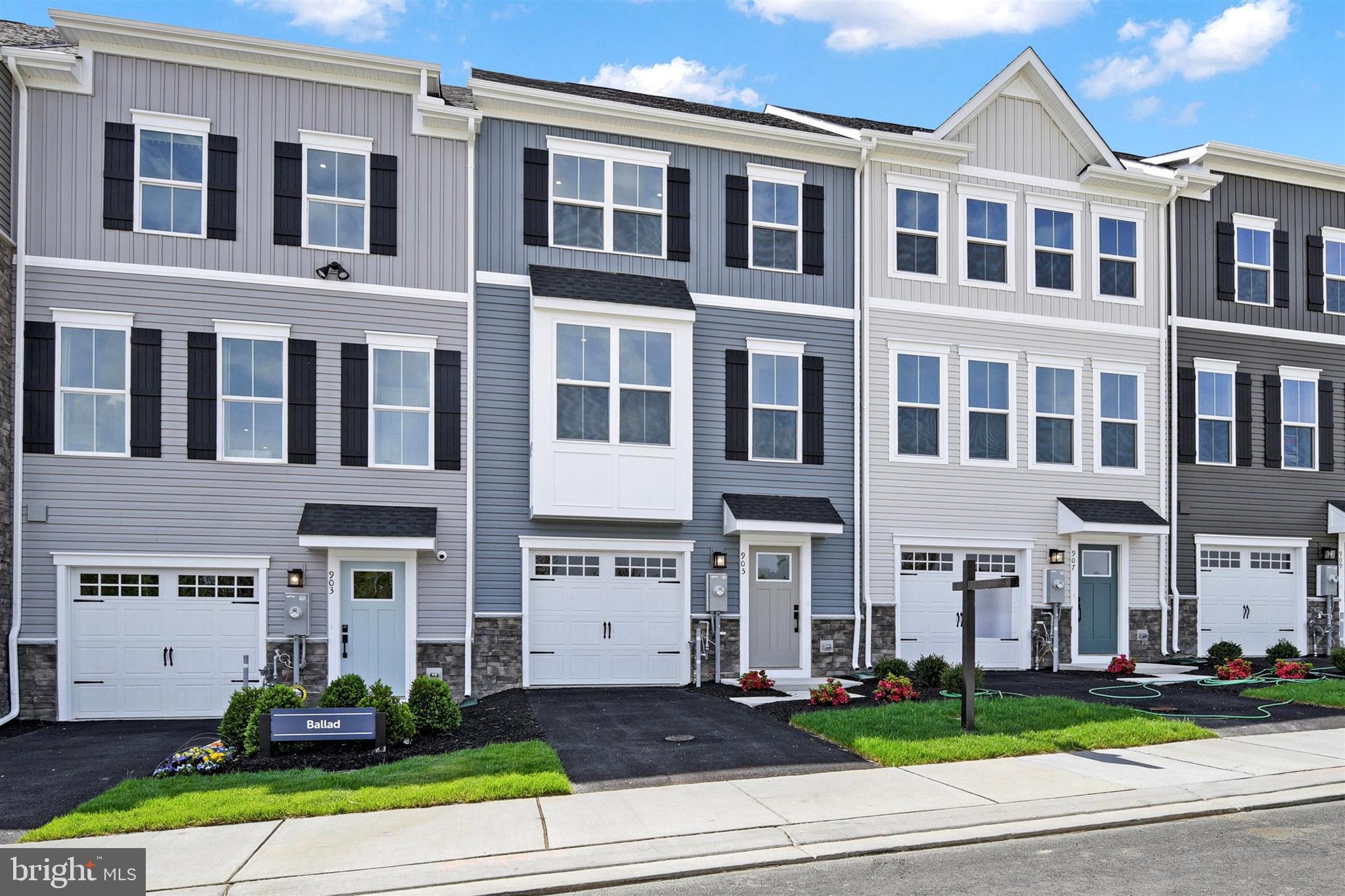 a front view of a residential apartment building with yard and green space