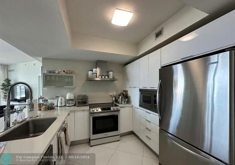 a kitchen with stainless steel appliances granite countertop a refrigerator sink and stove