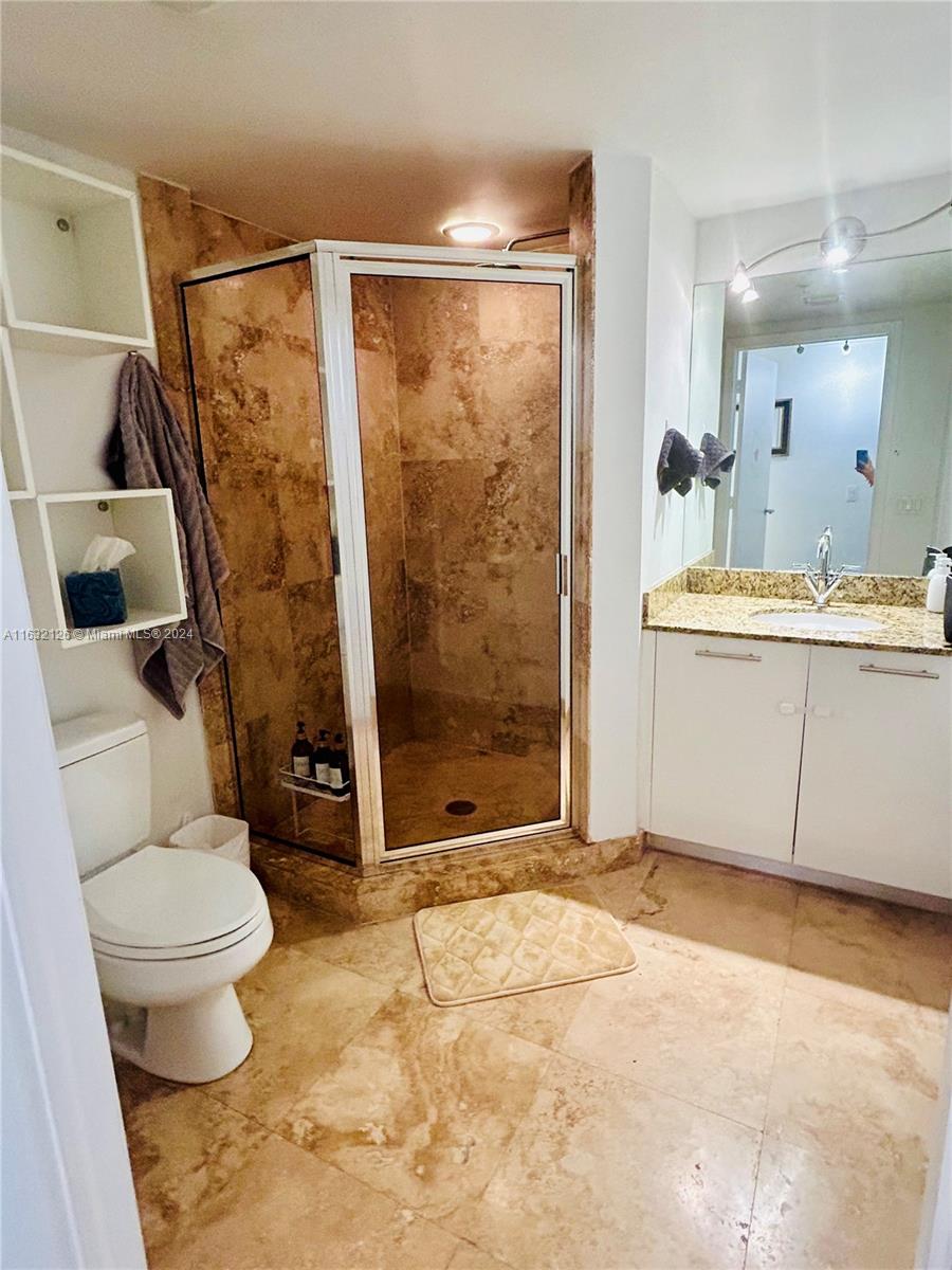 a bathroom with a granite countertop sink toilet and shower