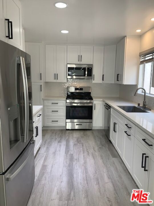 a kitchen with stainless steel appliances a stove a sink and a refrigerator