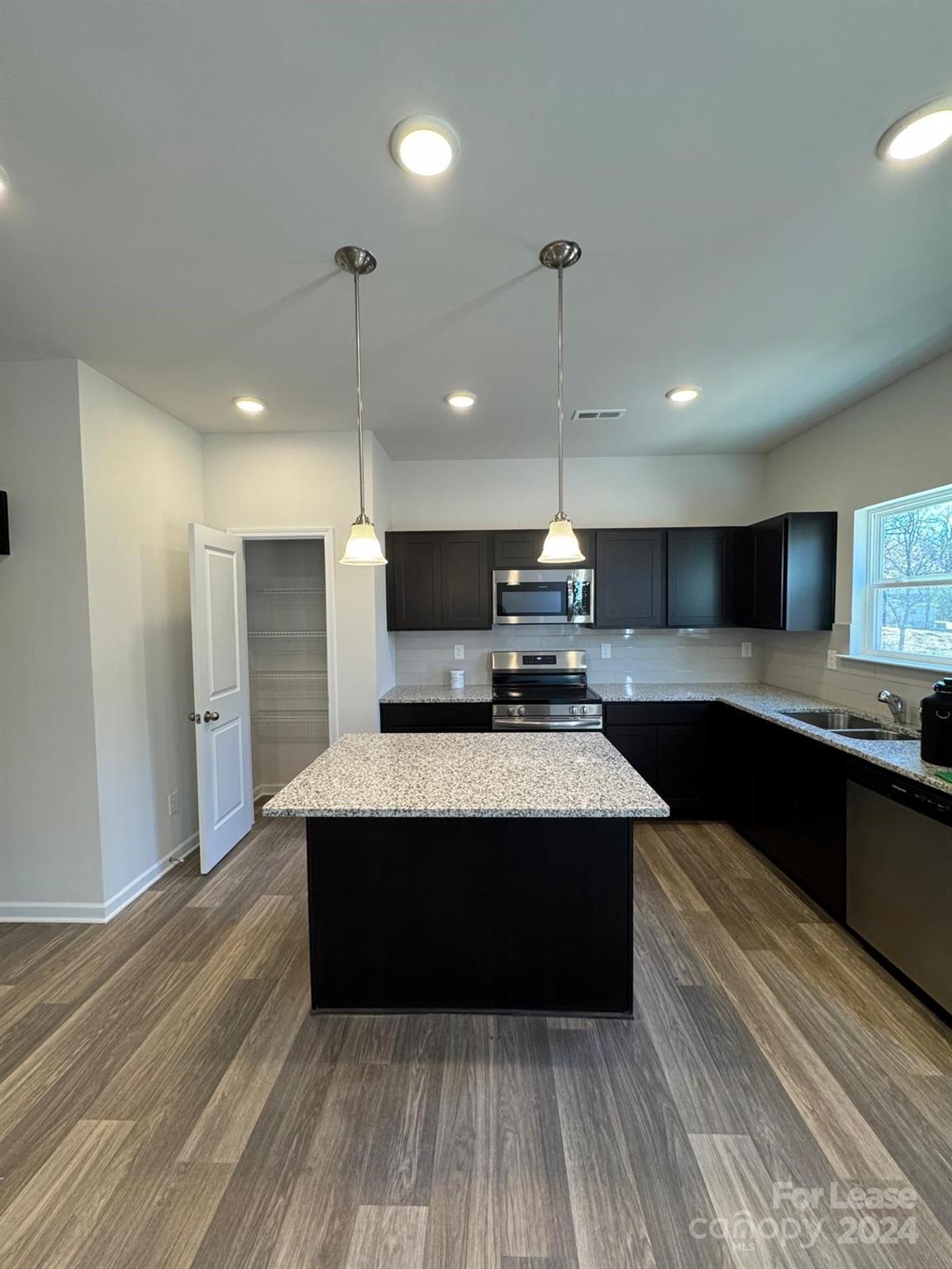 a large kitchen with kitchen island a sink stainless steel appliances and cabinets