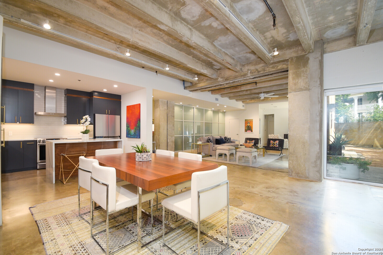 a dining room with stainless steel appliances kitchen island granite countertop a table chairs and a rug