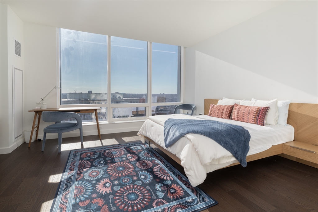 a bedroom with a bed wooden floor and a lamp on dresser