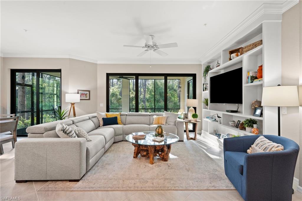 a living room with furniture a flat screen tv and a floor to ceiling window