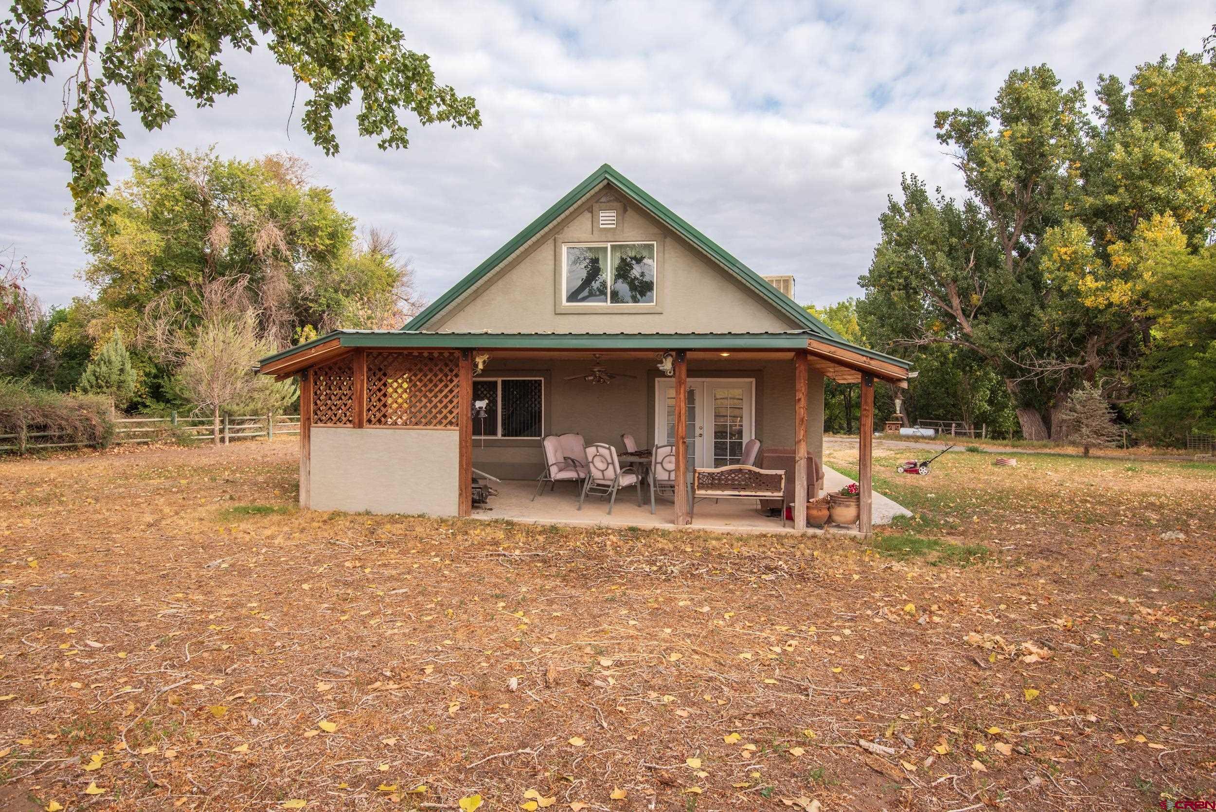 a front view of a house with yard and trees in the background