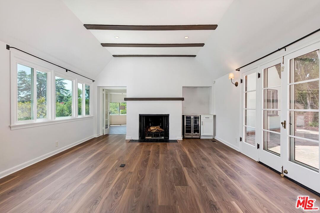 a view of an empty room with wooden floor fireplace and a window