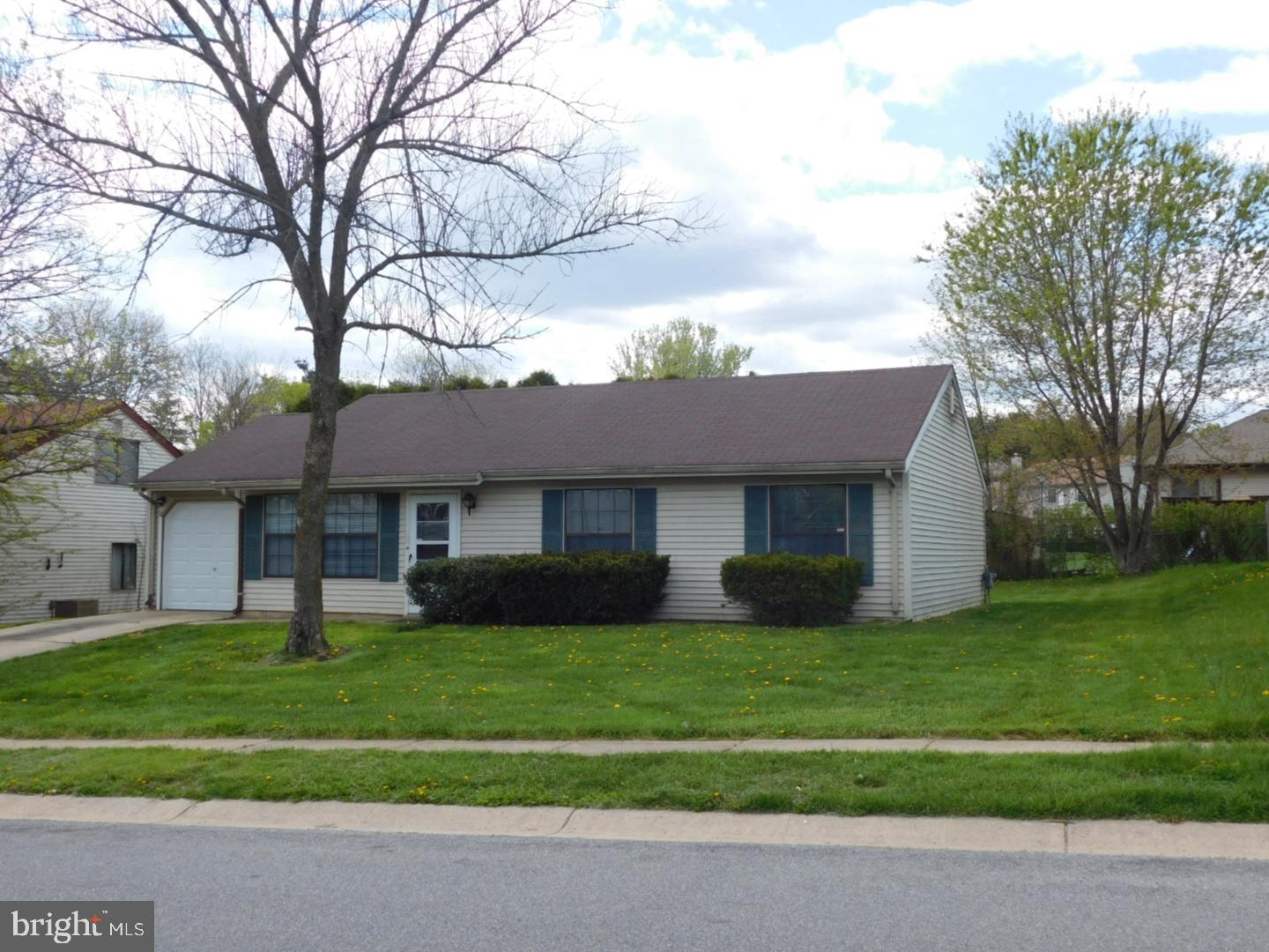 a view of a brick house with a big yard and large trees