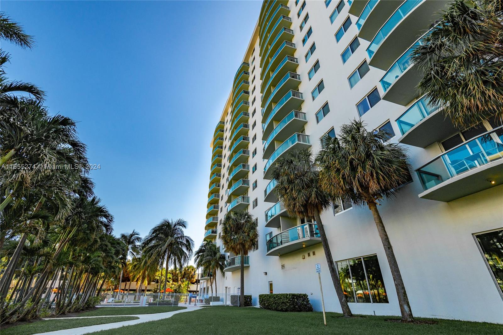 a front view of multi story residential apartment building with yard and sign board