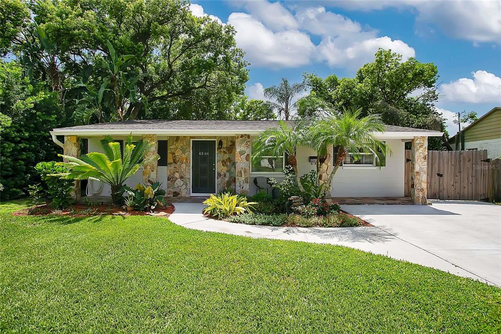 a front view of a house with a yard and potted plants